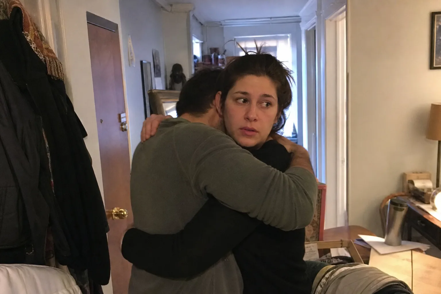 One partner looks uncertain during a reconciliation hug after an argument.