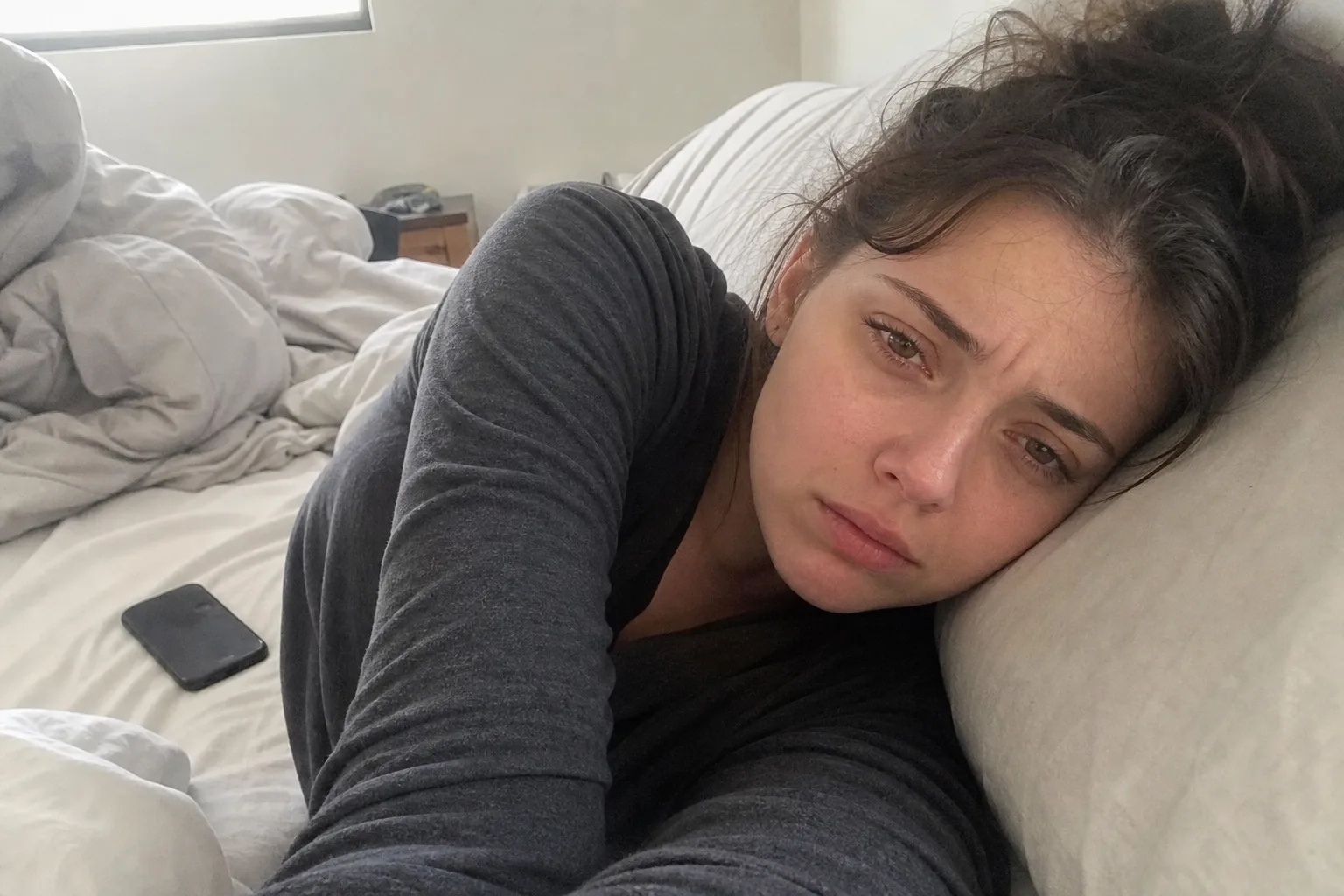A woman rests on her bed after her boyfriend ended the relationship.