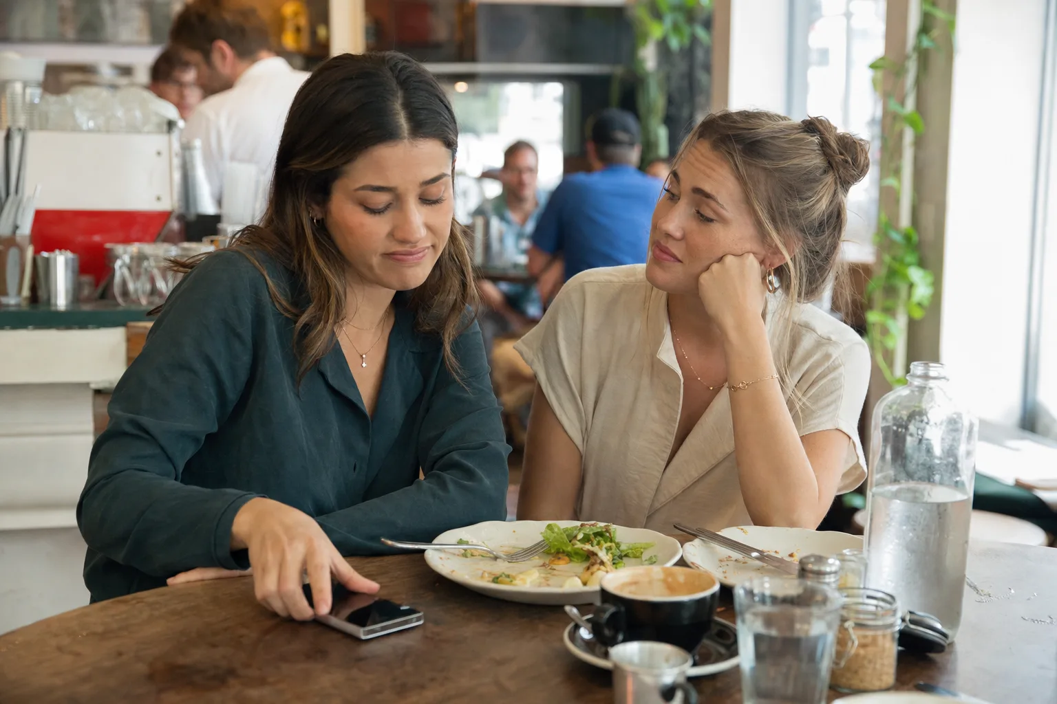 A woman turns her phone face-down while talking with a friend about being ghosted again.